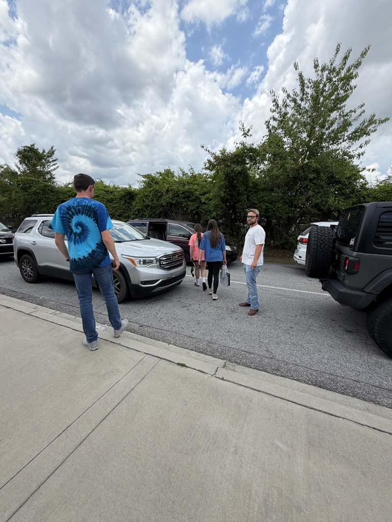 Teachers at car duty tell students goodbye as they watch them get into their cars on the last day of school before summer break.