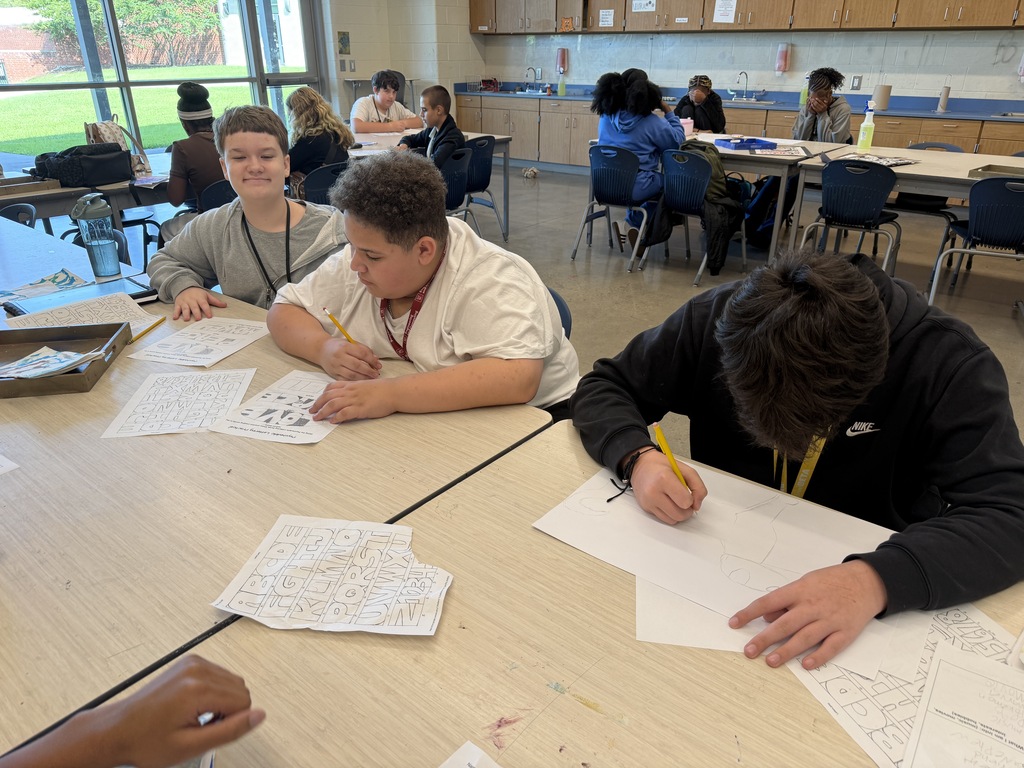 Students sit at a table in art class working on brainstorming their psychedelic drawings while and after viewing previous students' psychedelic artwork.