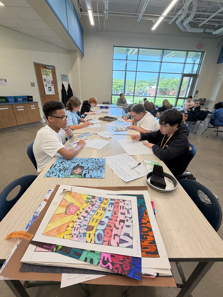 Students sit at a table in art class working on brainstorming their psychedelic drawings while and after viewing previous students' psychedelic artwork.
