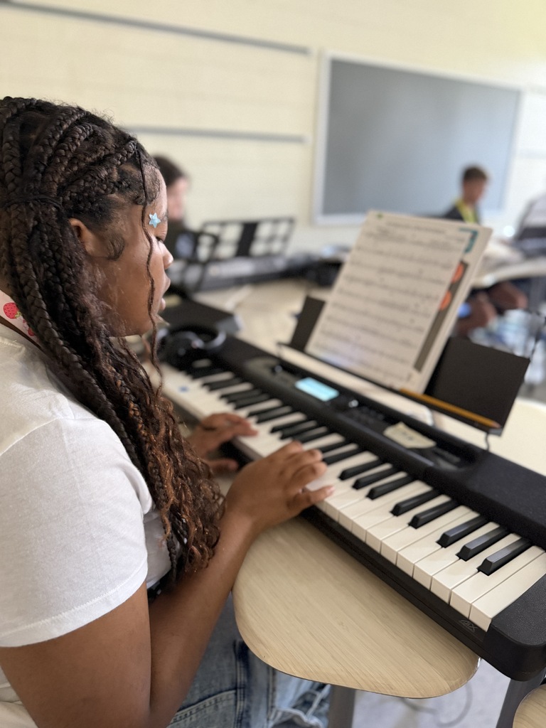 A female student is shown practicing on the piano keyboard.