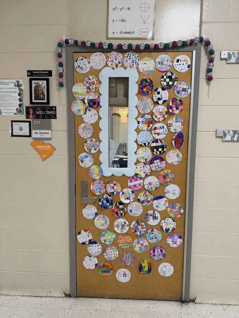 Picture of Ms. Branton's classroom door from the hallway looking at the door. The door is covered in circular disco balls that students decorated and wrote about some of their interests. Seen to the left of her door is her middle school photo, name placard, and other identifications that represent her as a teacher and her educational background.er 