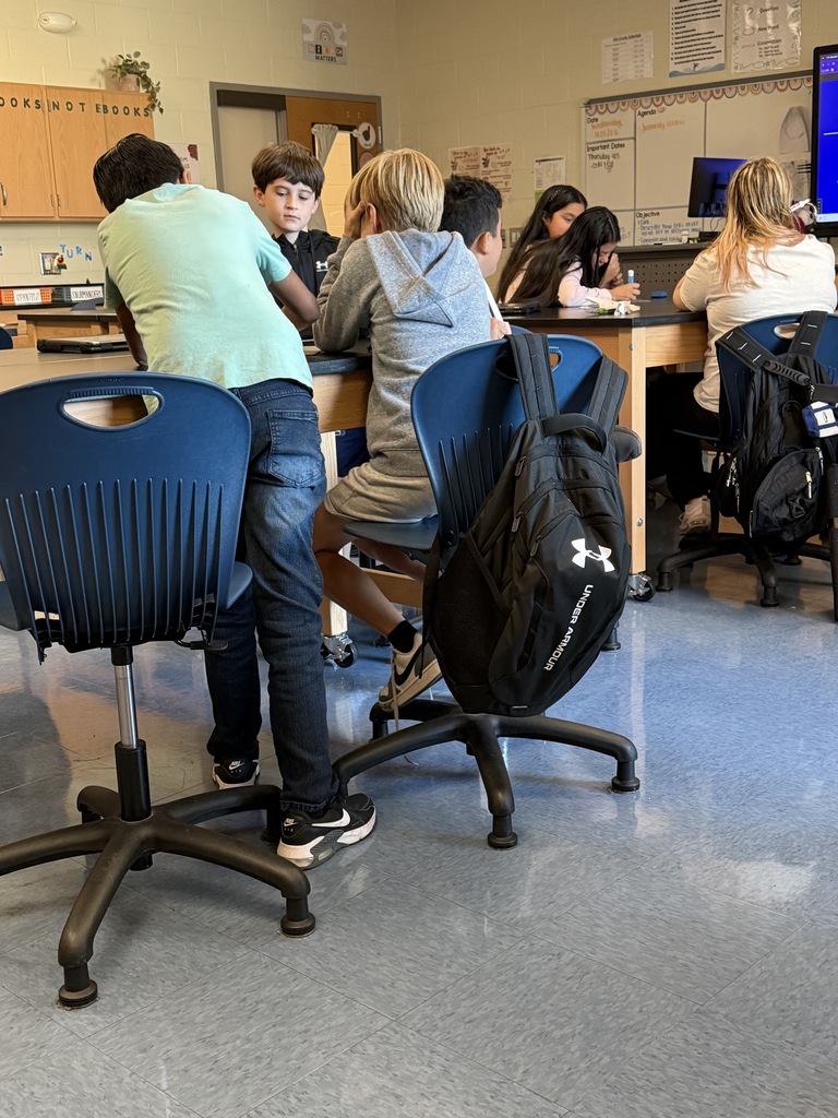 Students are shown sitting or standing at their science lab tables sorting through a question on paper.