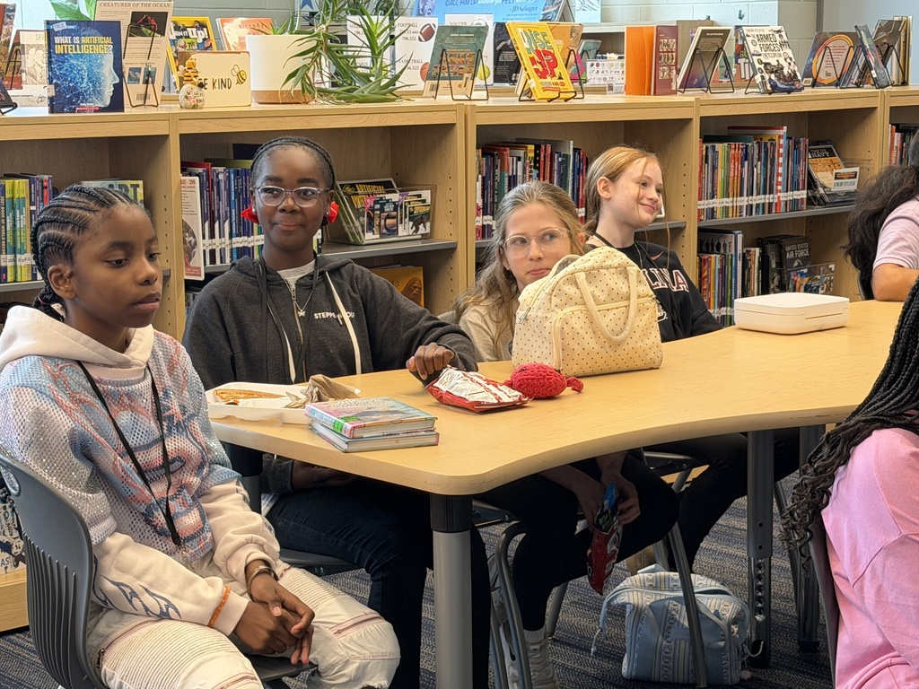 Students gathered in the library sitting at tables while eating lunch and participating in the Fulmer library and public library collaboration event.