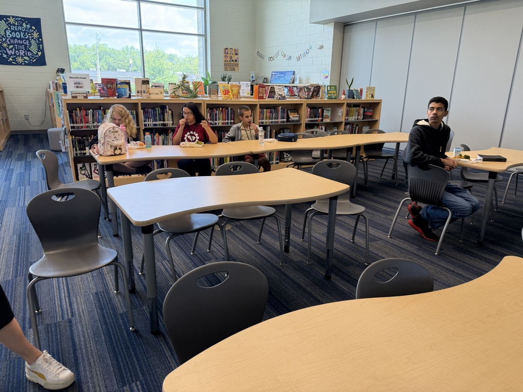 Students gathered in the library sitting at tables while eating lunch and participating in the Fulmer library and public library collaboration event.