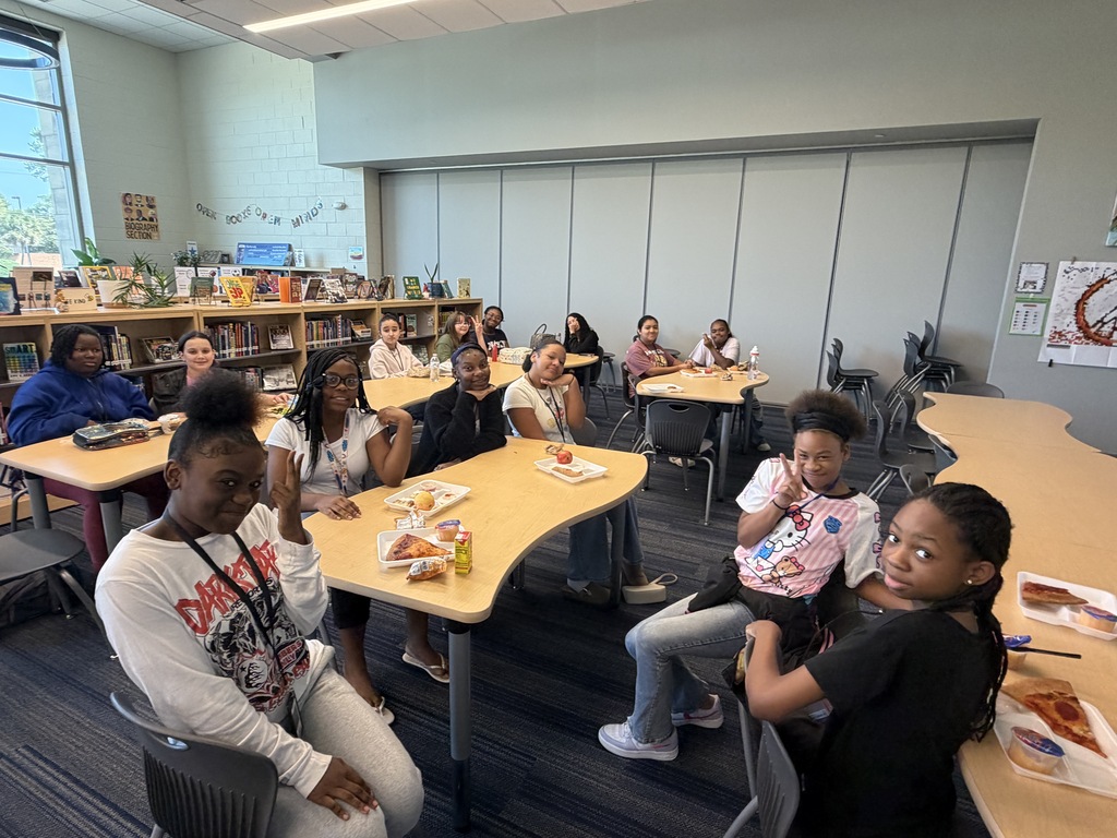 Students gathered in the library sitting at tables while eating lunch and participating in the Fulmer library and public library collaboration event.