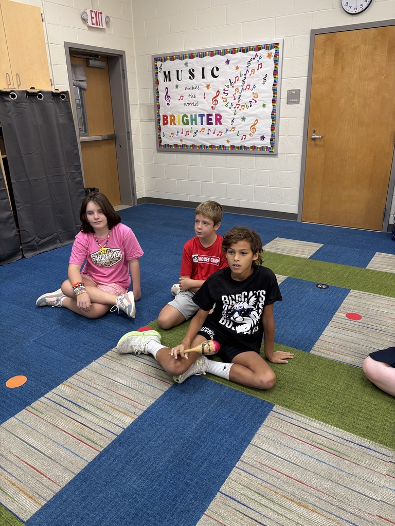 3 students sitting on the floor wearing spirit shirts