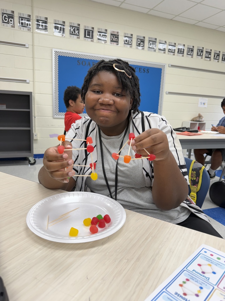 A student is shown with the DOT candy structure she built using toothpicks and DOT gummy candy.