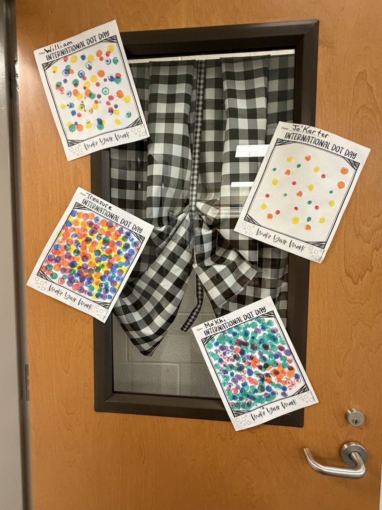 Four pieces of artwork that show how the students used different color dot stampers are posted on the outside of a classroom door on display.