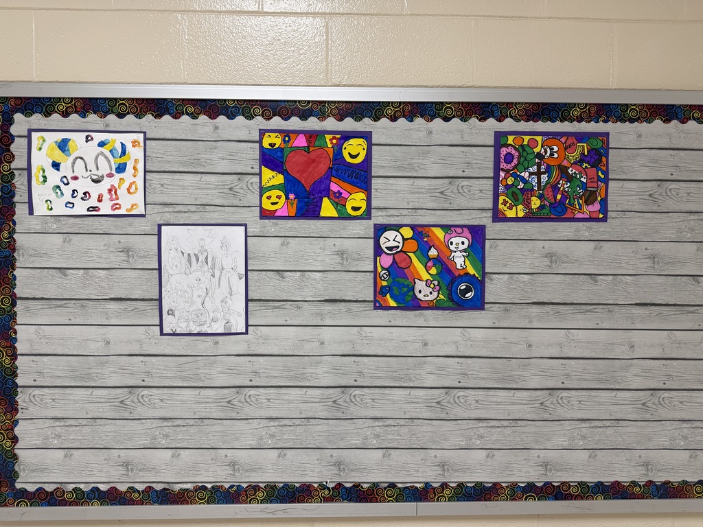 A bulletin board in the school hallway contains five different pieces of student artwork. Three out of the five are filled with various colors, the other has some colors and white space, and the last is pencil sketch.