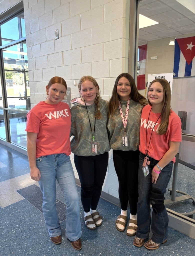 Four students stand side by side smiling at the camera wearing the exact clothing attire for Twin Day at school. Two students on the end of the row of four students have matching outfits, and the two students in the middle have matching outfits.
