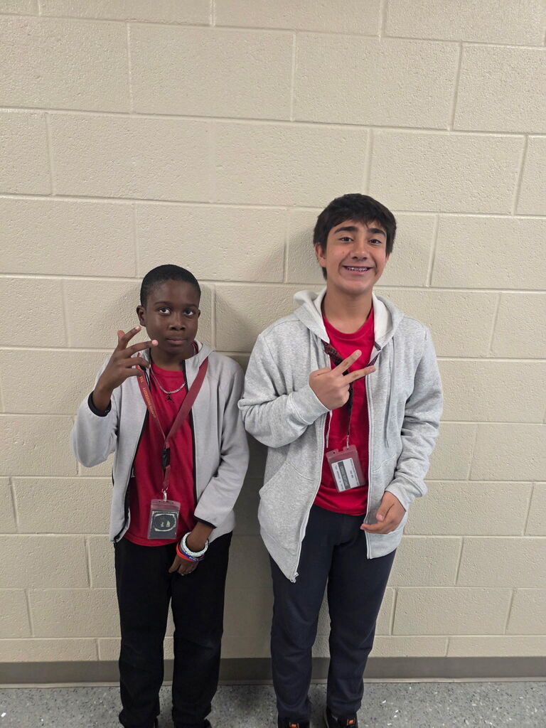 Two students stand side by side smiling at the camera wearing the exact clothing attire for Twin Day at school. 