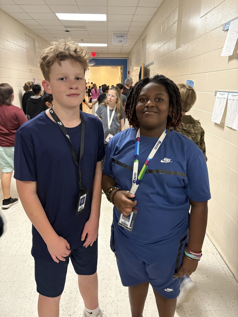 Two students stand side by side smiling at the camera wearing the exact clothing attire for Twin Day at school. 