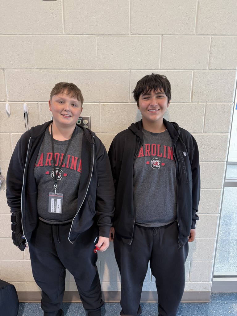 Two students stand side by side smiling at the camera wearing the exact clothing attire for Twin Day at school. 