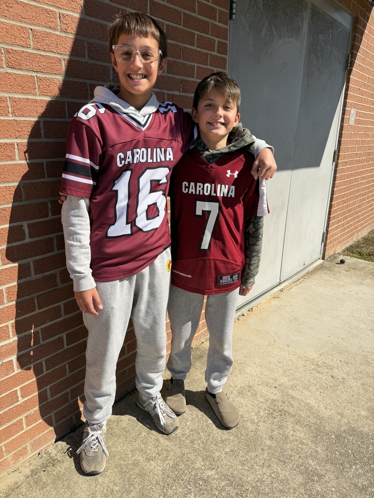 Two students stand side by side smiling at the camera wearing the exact clothing attire for Twin Day at school. 