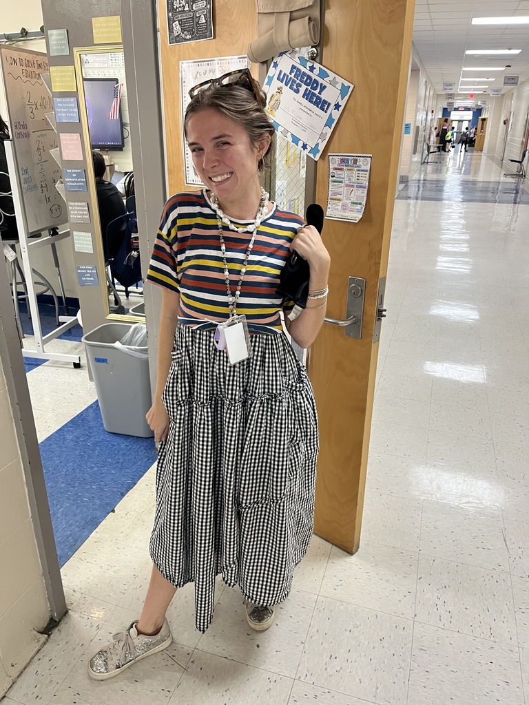 One teacher stands smiling at the camera wearing mismatched clothing.