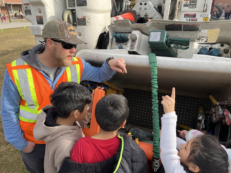 Dominion Energy volunteers talk with students in front of their bucket truck
