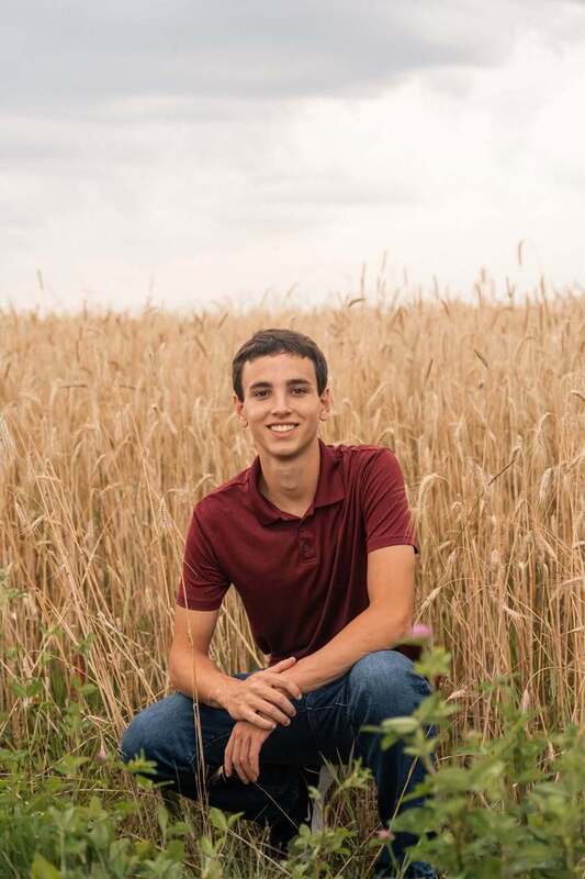 boy in maroon shirt sitting in a field