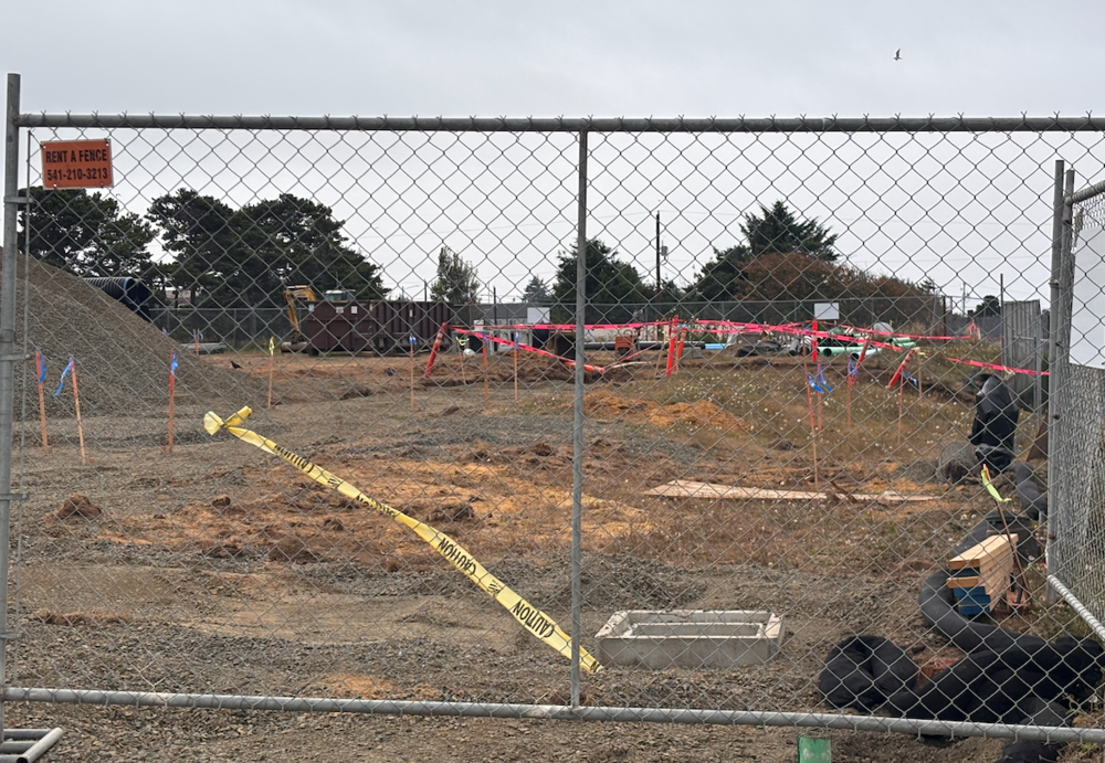 Dirt and construction equipment behind a chain link fence