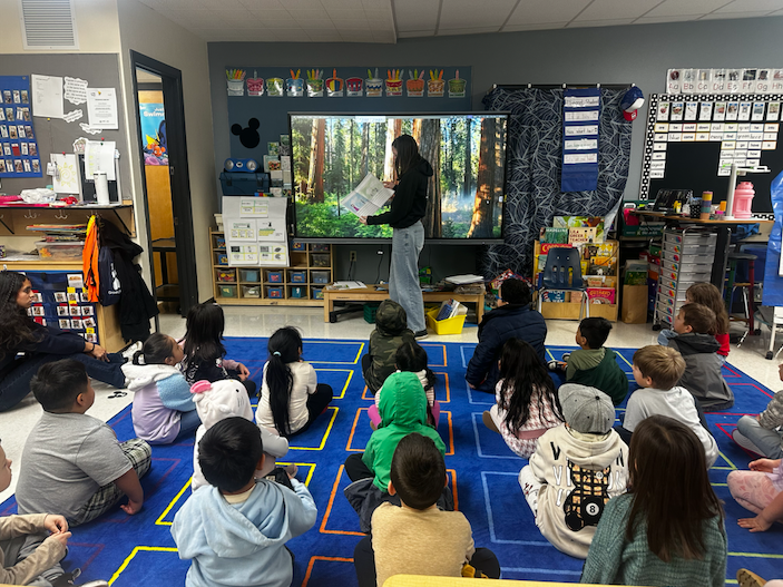 Middle school female student reading to elementary students