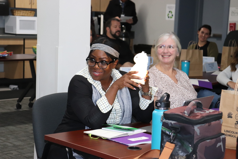 Woman smiling holding a unicorn toy with a gray haired woman also smiling