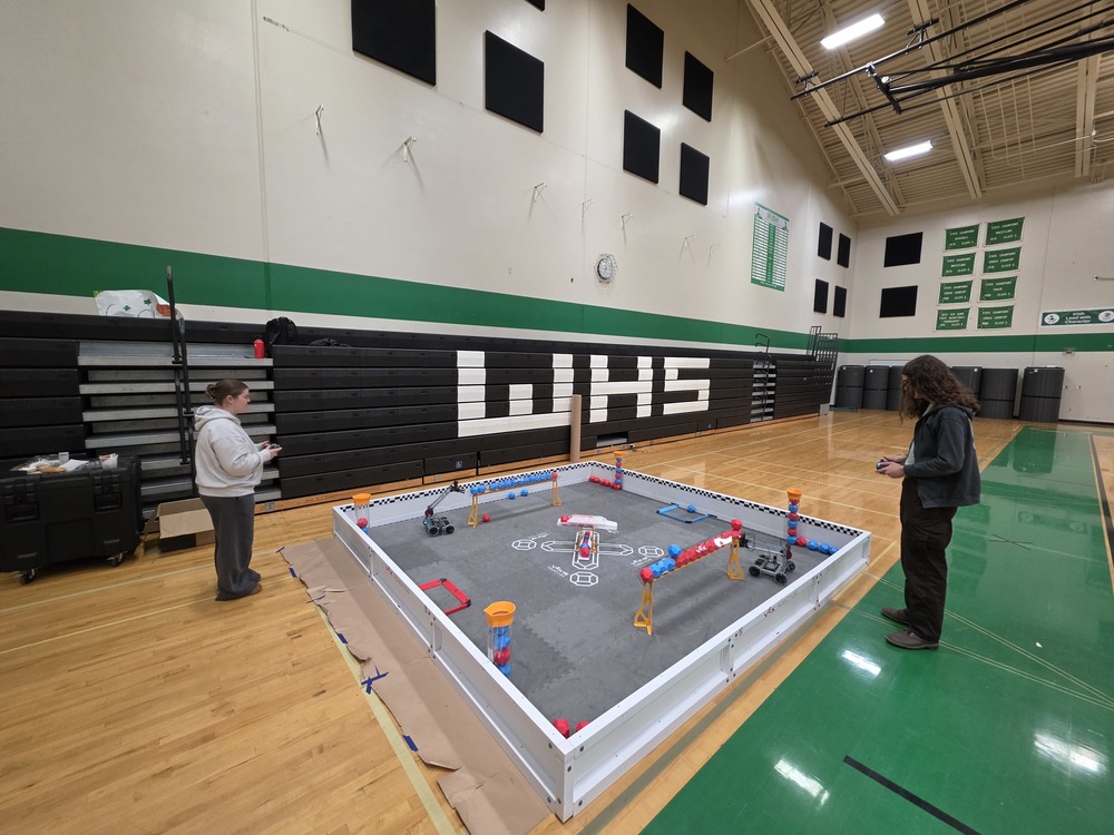 Students standing in the gym using remote controlled machines