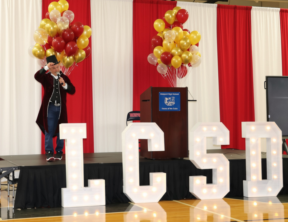 Man in top hat standing on stage with LCSD lights in front