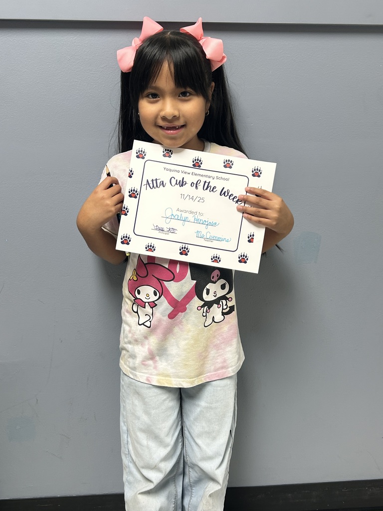 Smiling student holding up Atta Cub Kid of the Week certificate