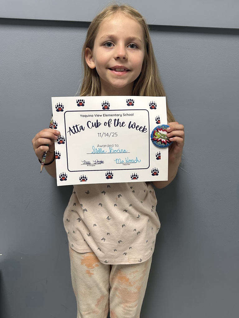 Smiling student holding up Atta Cub Kid of the Week certificate