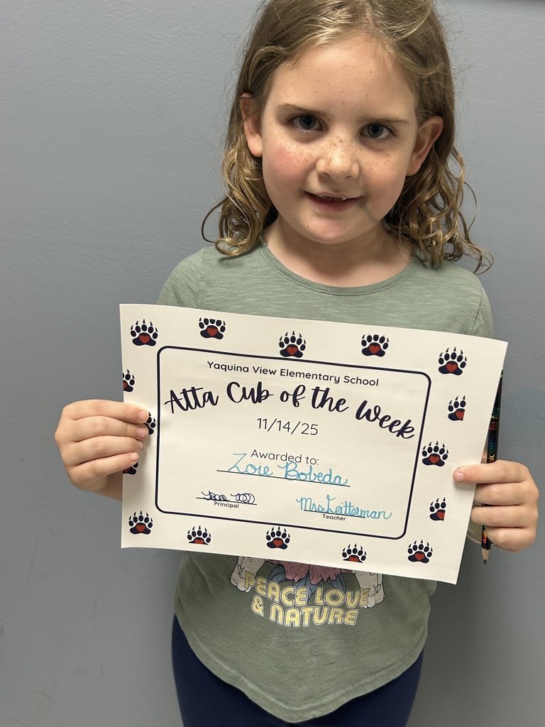 Smiling student holding up Atta Cub Kid of the Week certificate