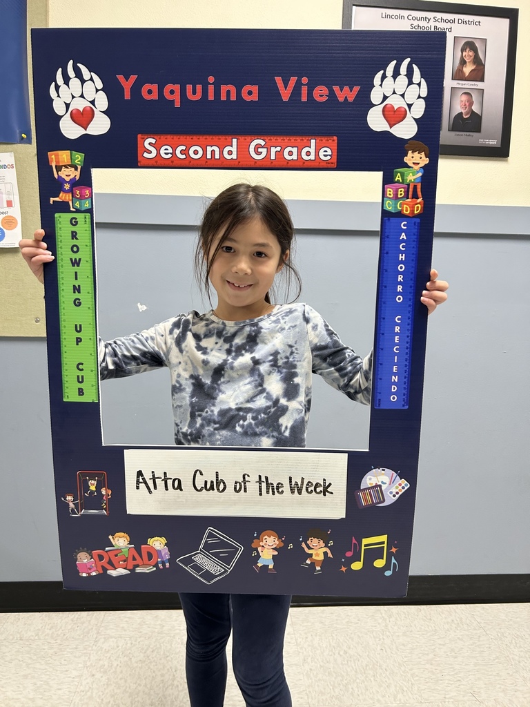 Smiling girl student holding up Atta Cub Kid of the Week picture frame.
