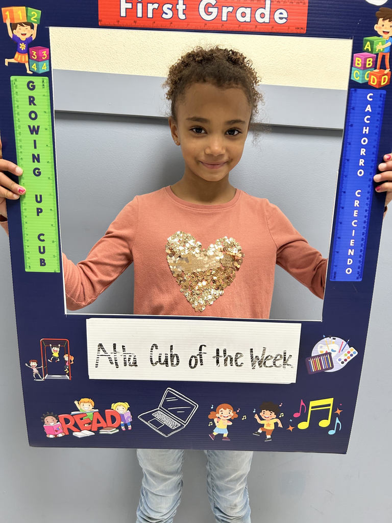 Smiling girl holding up Atta Cub kid of the week picture frame. 