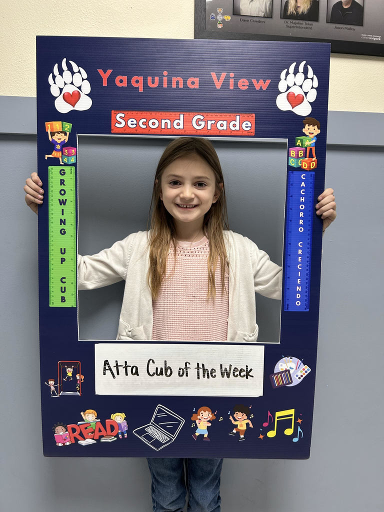 Smiling girl holding up Atta Cub kid of the week picture frame. 