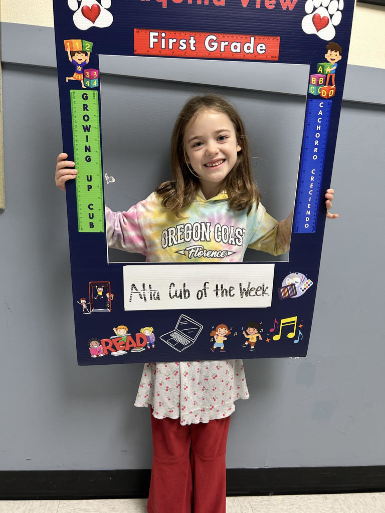Smiling girl holding up Atta Cub kid of the week picture frame. 