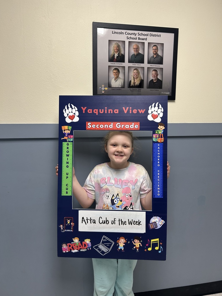 Smiling girl holding Atta Cub kid of the week frame. 