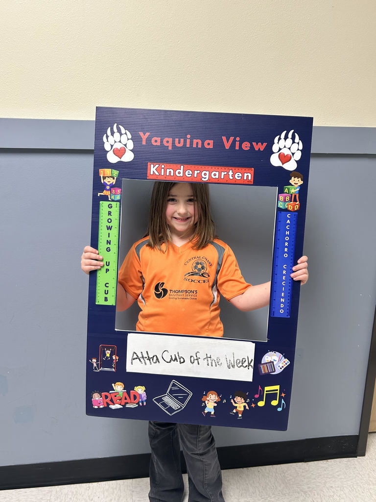 Smiling girl holding Atta Cub kid of the week frame