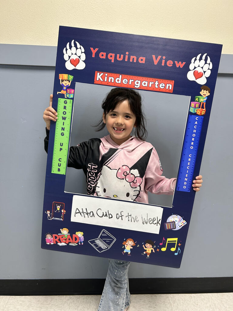 Smiling girl holding Atta Cub Kid of the week picture frame.