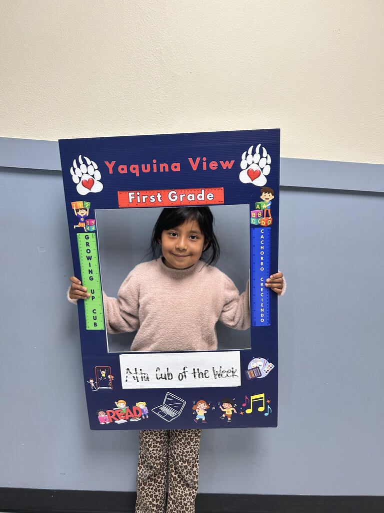 Smiling girl holding Atta Cub Kid of the week picture frame.