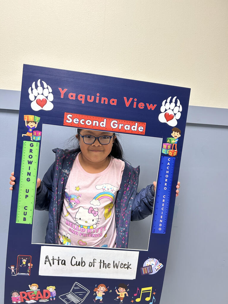 Smiling girl holding Atta Cub Kid of the week picture frame.