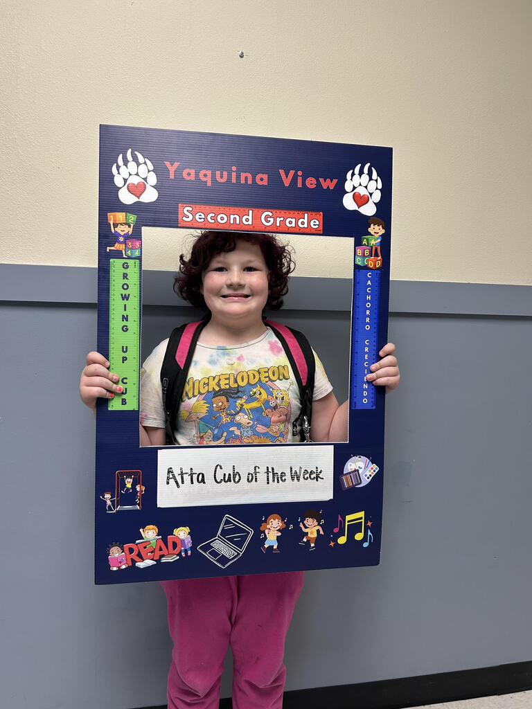 Smiling girl holding Atta Cub Kid of the week picture frame.
