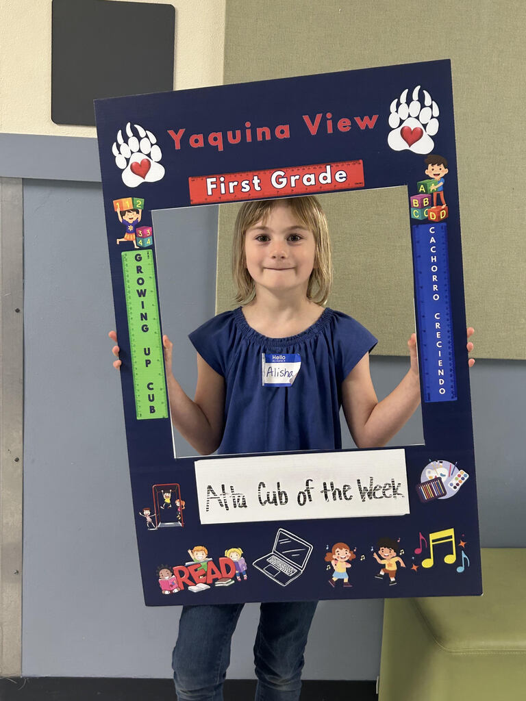 Smiling girl holding Atta Cub Kid of the week picture frame.