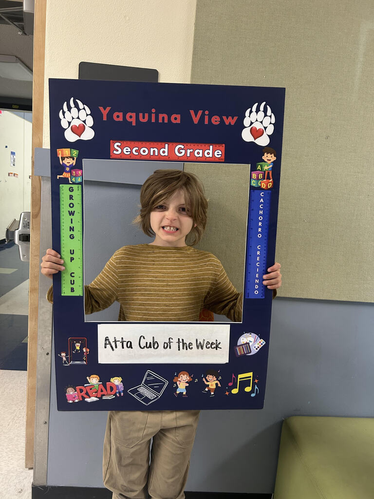 Smiling boy holding Atta Cub Kid of the week picture frame.