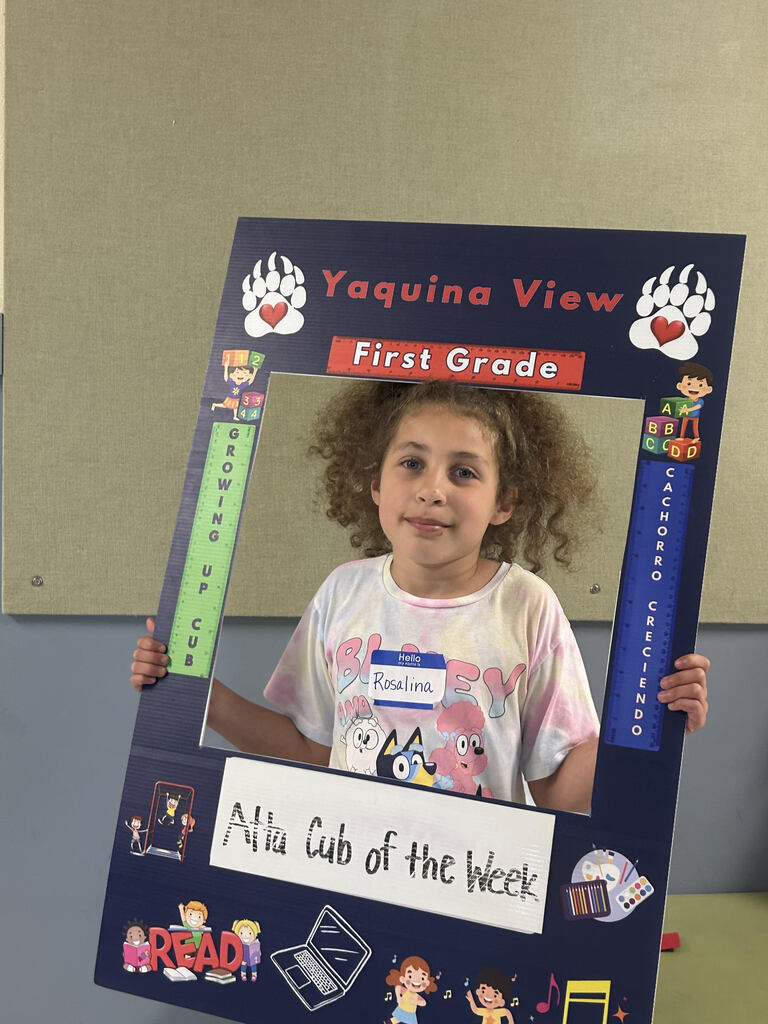 Smiling girl holding Atta Cub Kid of the week picture frame.