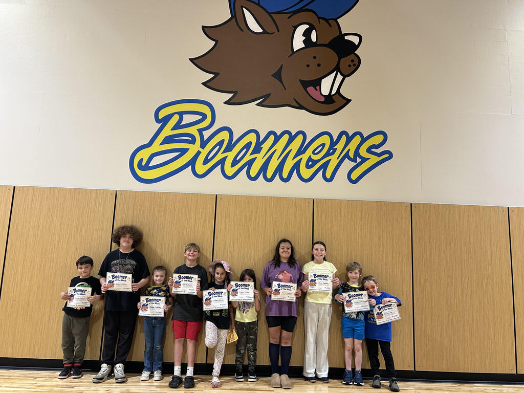 Boys and girls of various ages holding Boomer of the Week certificates and smiling.