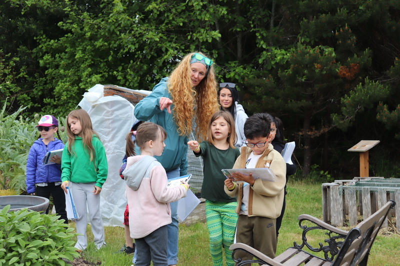 A group of students with clipboards stand in a garden