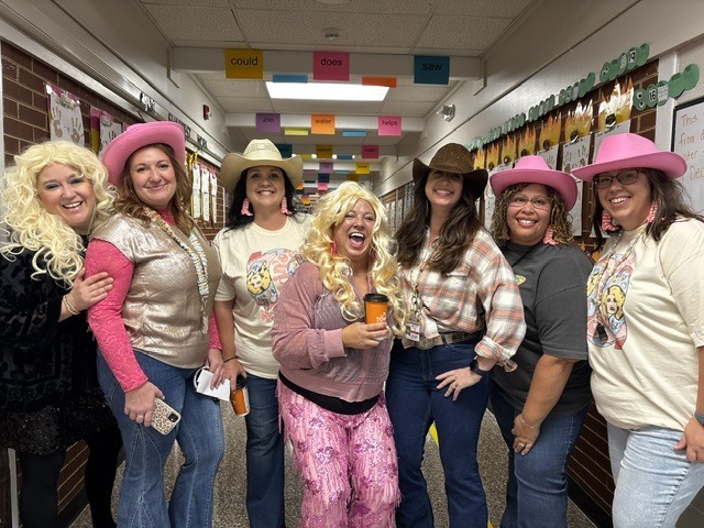 teachers dressed as Dolly Parton pose for a group picture