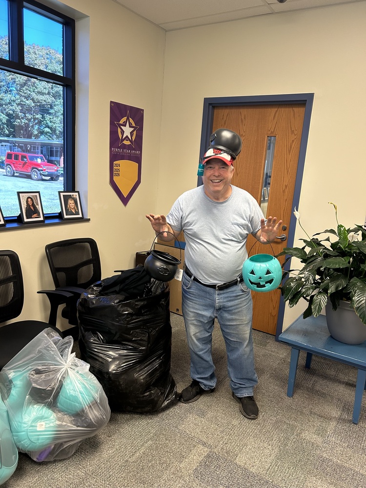 Man standing in an office holding Halloween teal pumpkin baskets.