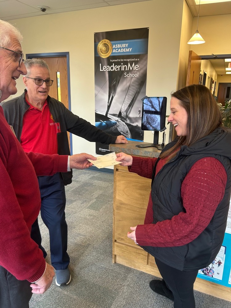 Two Knights of Columbus members give a check to a teacher
