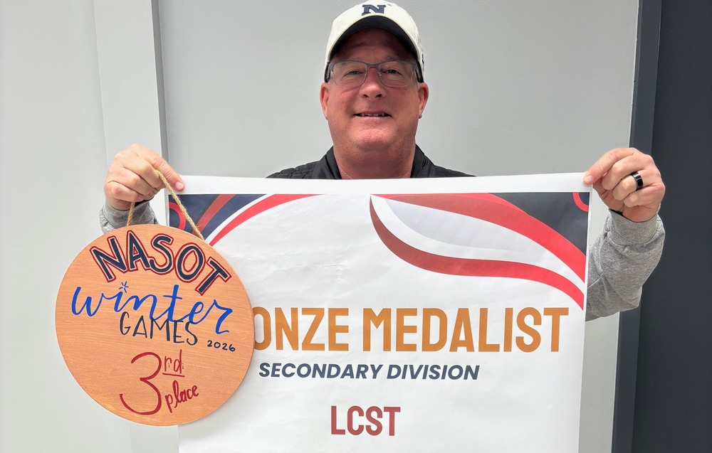 Mr. Clary displaying a banner for LCST placing 3rd in NASOT Winter Games among high schools.