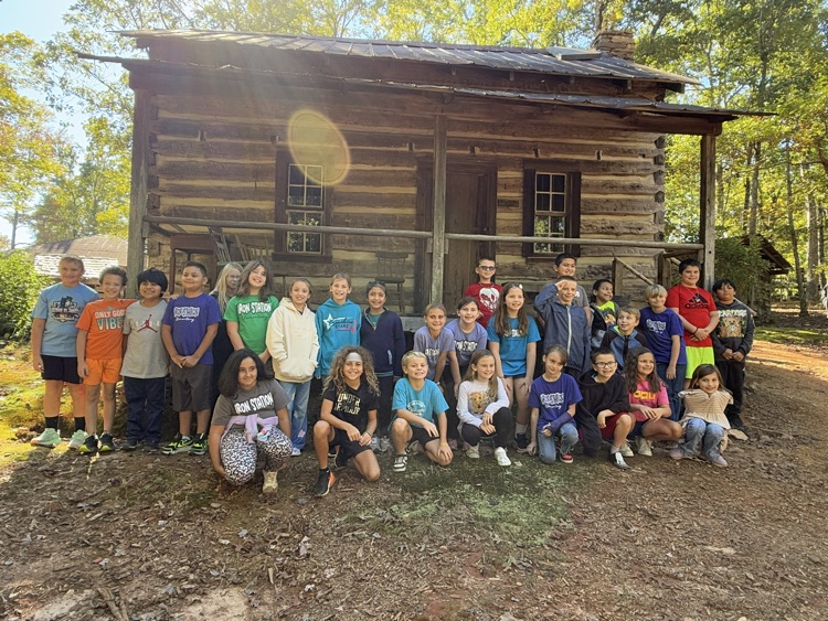 Students pose outside of a cabin at Hart Square.