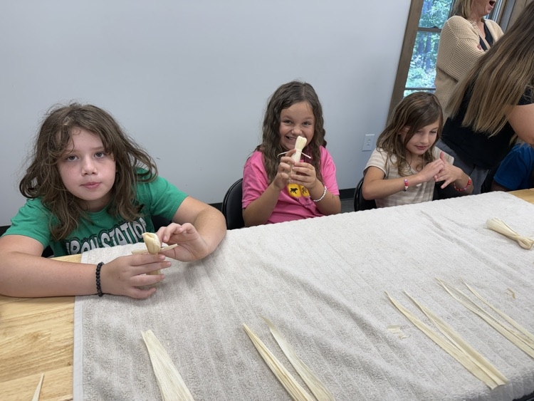 Students make corn husk dolls.